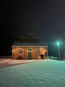 - un bâtiment en bois avec un panneau la nuit dans l'établissement The Saloon Cabin Retreat, à Hedgesville