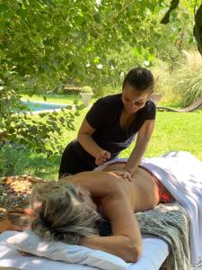 a woman is getting a massage from a therapist at La Noccemada, Bastide secrète et Table Gastronomique in Saint-Julien