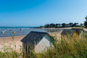 two buildings on a beach with boats in the water at Mobilhome kervoyal 56 in Damgan