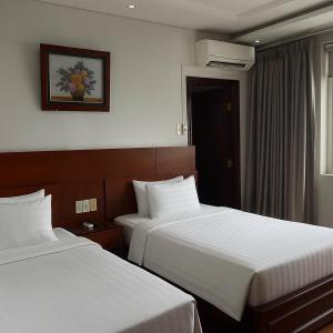 a hotel room with two beds and a window at Van Ha Boutique Hotel Etown - Nhà Ga T3 in Ho Chi Minh City