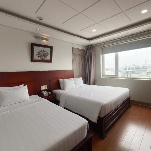 a hotel room with two beds and a window at Van Ha Boutique Hotel Etown - Nhà Ga T3 in Ho Chi Minh City +13 photos