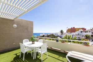 a white table and chairs on a balcony with the ocean at Eden Rentals Pure Abona in Poris de Abona