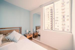 a bedroom with a white bed and a window at Apartaestudio Norte de Armenia in Armenia