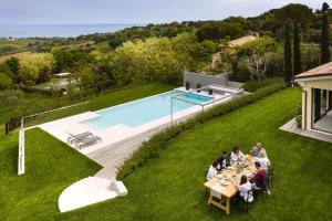 a group of people sitting at tables on a lawn next to a pool at Villa Vecchioni in Civitanova Alta
