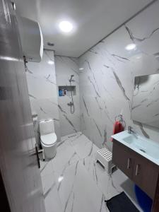 a white bathroom with a toilet and a sink at Appartement à residence MALAGA BEACH in Mansouria