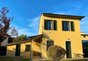 a yellow house with green shuttered windows and a tree at Nazario Sauro - Lucca by the walls in Lucca