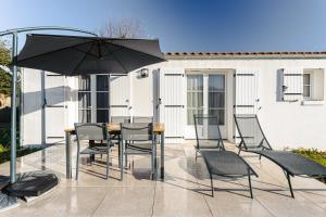 a patio with a table and chairs and an umbrella at Reminette in Les Sables Vignier