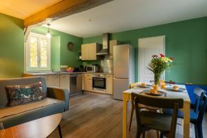 a kitchen with green walls and a table with a vase of flowers at Cocon' Aire Charmant appartement au calme, proche centre, wifi in Aire-sur-lʼAdour