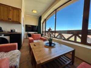 a living room with a table and a large window at Murphys Lodge panorama apartment in Bansko