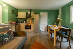 a living room with a table and a kitchen with green walls at Cocon' Aire Charmant appartement au calme, proche centre, wifi in Aire-sur-lʼAdour +7 photos