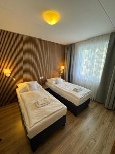 a hotel room with two beds and a window at Hotel ROSE Břeclav in Břeclav
