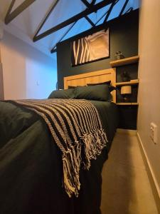a bedroom with a large black bed with a blanket on it at atnine in Welkom