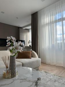 a living room with a vase of flowers on a table at City Centre Apartment with Cathedral View, Self Check-in in Šiauliai
