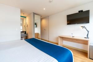 a bedroom with a bed with a tv on the wall at Pop Art Hotel Tocancipá y Centro de Convenciones in Tocancipá