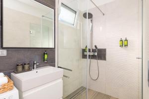 a white bathroom with a sink and a shower at LuxArt City Spa Gallery Residence Krk in Krk +23 photos