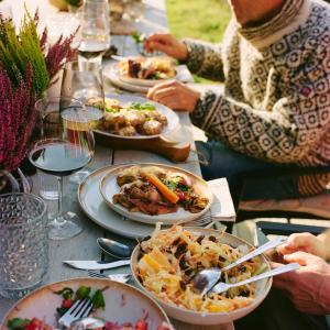 eine Gruppe von Menschen, die um einen Tisch mit Teller Essen sitzen in der Unterkunft Kyn Sjøstuer in Stavang