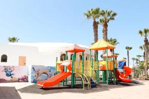 um parque infantil em frente a um edifício com palmeiras em Coco Canaria em Corralejo