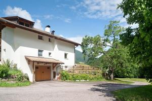 a large white house with a driveway next to it at Apartment Bodnerhof in Collepietra
