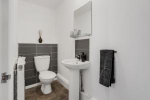 een witte badkamer met een toilet en een wastafel bij Bright 1-Bed Flat, Near Station, Fast Wi-Fi in Wellingborough