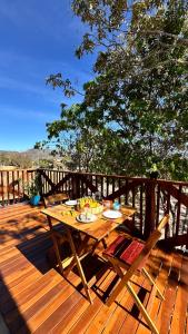 a wooden deck with a table and chairs on it at Chalés Refúgio da Sil in Cavalcante