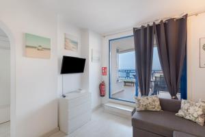a living room with a couch and a window at Taurito's sea sunset view in Taurito