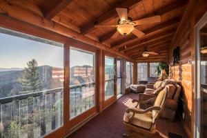 a living room with a ceiling fan and large windows at Alpine Vista in Blowing Rock