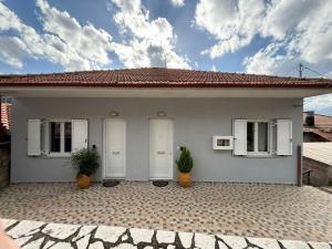 a white house with two windows and two plants at Cozy Home in Klitoria