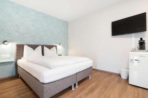 ヘルボルツハイムにあるGästehaus Heimeligの壁にテレビが付いたベッドのある寝室