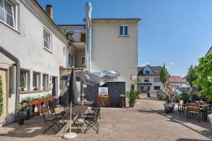 a patio with chairs and an umbrella in front of a building at Gasthof Bräuhaus Lepple Apartments in Vöhringen
