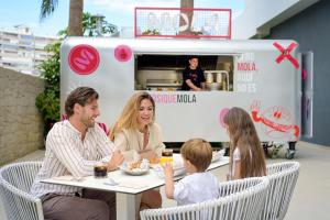 アリカンテにあるPort Alicante City & Beachのフードトラックの前のテーブルに座っている家族 +130枚の写真