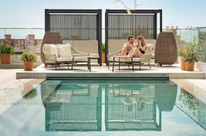 アリカンテにあるPort Alicante City & Beachのスイミングプールの横の椅子に座る女性2名