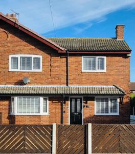 une maison en briques avec une clôture devant elle dans l'établissement 3 Bedroom Village Stay - Comfort & Charm in Yorkshire, à Kippax