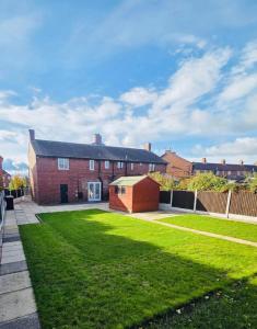 une grande maison en briques avec une cour verdoyante dans l'établissement 3 Bedroom Village Stay - Comfort & Charm in Yorkshire, à Kippax