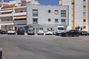 a parking lot with cars parked in front of a building at Refúgio Estrela do Mar in Quarteira