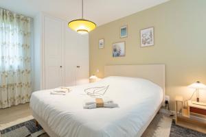 une chambre avec un lit blanc avec deux serviettes dessus dans l'établissement Villa Dune - 180m de la plage, à Penmarcʼh