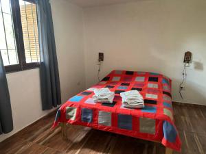 a bedroom with a bed with a red and blue blanket at Cabaña El Quebrachal in Valle Hermoso