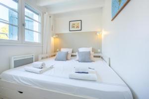 a white bedroom with a large white bed at Appartement Le Capitaine in Cap-Ferret