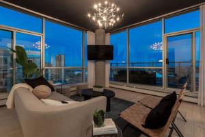 a living room with a chandelier and large windows at 2 Storey Penthouse Panoramic Views Parking Stampede in Calgary