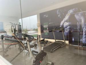 Una sala con gimnasio con pantalla grande. en Oasis Park Residences, en Accra