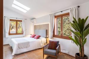 a white bedroom with a bed and a chair at Sembat de Mar in Cala Millor +27 photos