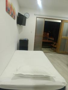 a white bed in a room with a clock on the wall at Mango Beach in San Bernardo del Viento