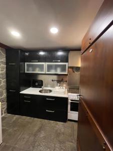 - une petite cuisine avec des placards noirs et un évier dans l'établissement Cozy Cottage, à Praia da Vitória