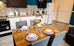 リバプールにあるLodginet Stays - County Luxe - 2BR Flat 1の皿とグラスが置かれた木製のテーブルと、ひまわりが入った花瓶 +14枚の写真
