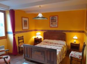 a bedroom with yellow walls and a bed and two lamps at Les Ormeaux in Milhars