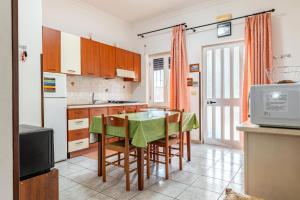 Una cocina con mesa y sillas y un refrigerador. en Oasi, en Torre Santa Sabina