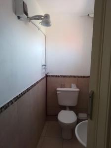 a bathroom with a white toilet and a sink at Casita Los Robles in Rosario de Lerma