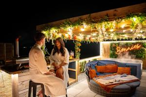 a man and woman sitting on a patio with a bar at Tan Y Bryn Glamping in Conwy +164 photos