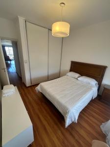 a bedroom with a bed with a white sheets and a light at Depto 3 de Febrero 235 in Venado Tuerto