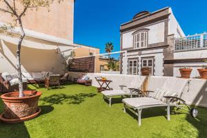 a patio with grass and chairs and a building at Santa Barbara Vegueta in Triana