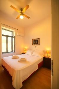 a bedroom with a white bed with a ceiling fan at Harmony Apartment Pythagoreio Samos Center in Pythagoreio +25 photos
